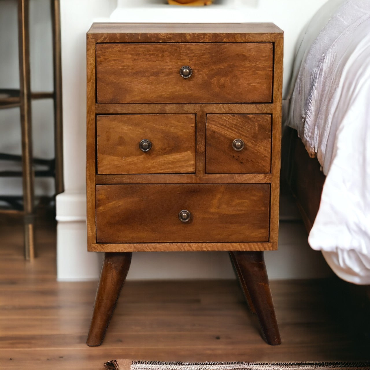 4 Drawer Chestnut Nightstand made from solid mango wood with smooth finish, four drawers, and Nordic-style legs. Full view by a bedside