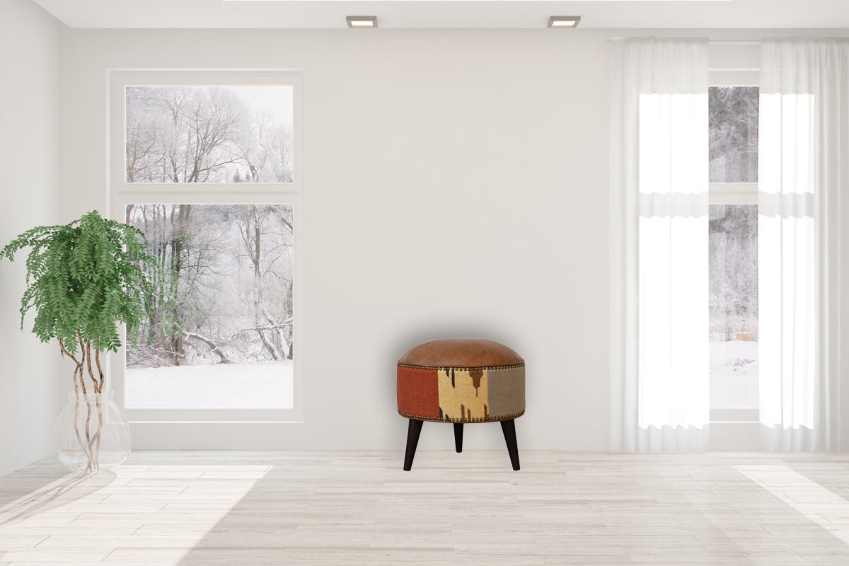 Durrie & Leather Mixed Footstool with Nordic-style legs, buffalo leather, and durrie print. Footstool positioned in a living space.