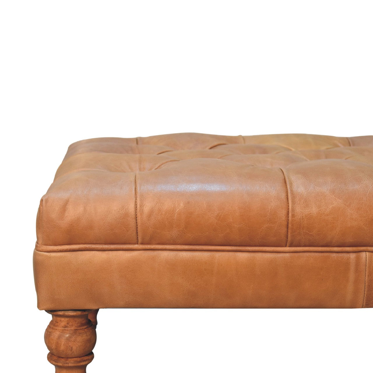 Tan buffalo leather ottoman with solid mango wood base, deep-buttoned top, and light walnut hand-turned feet. Half of ottoman view outlined leather view